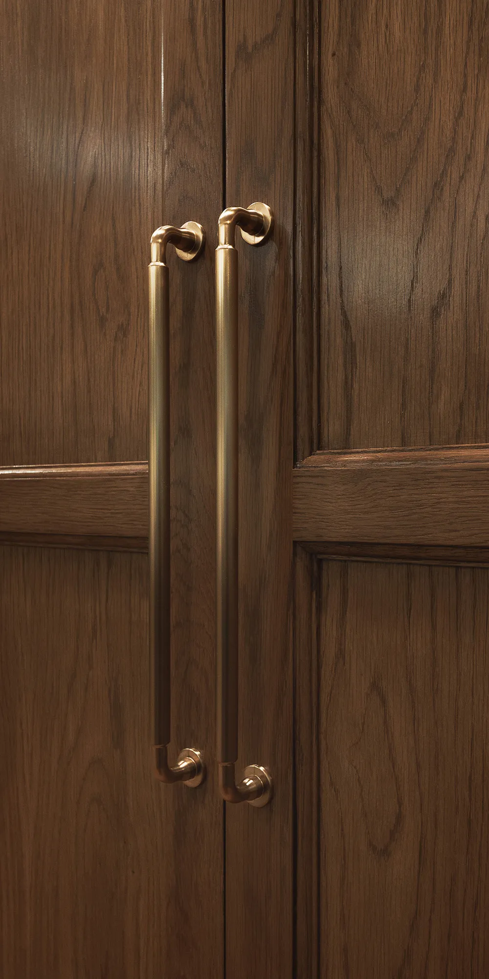 Long brass pulls on dark walnut cabinet doors